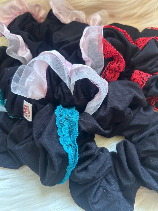 Set of black scrunchies with lace details on a light background