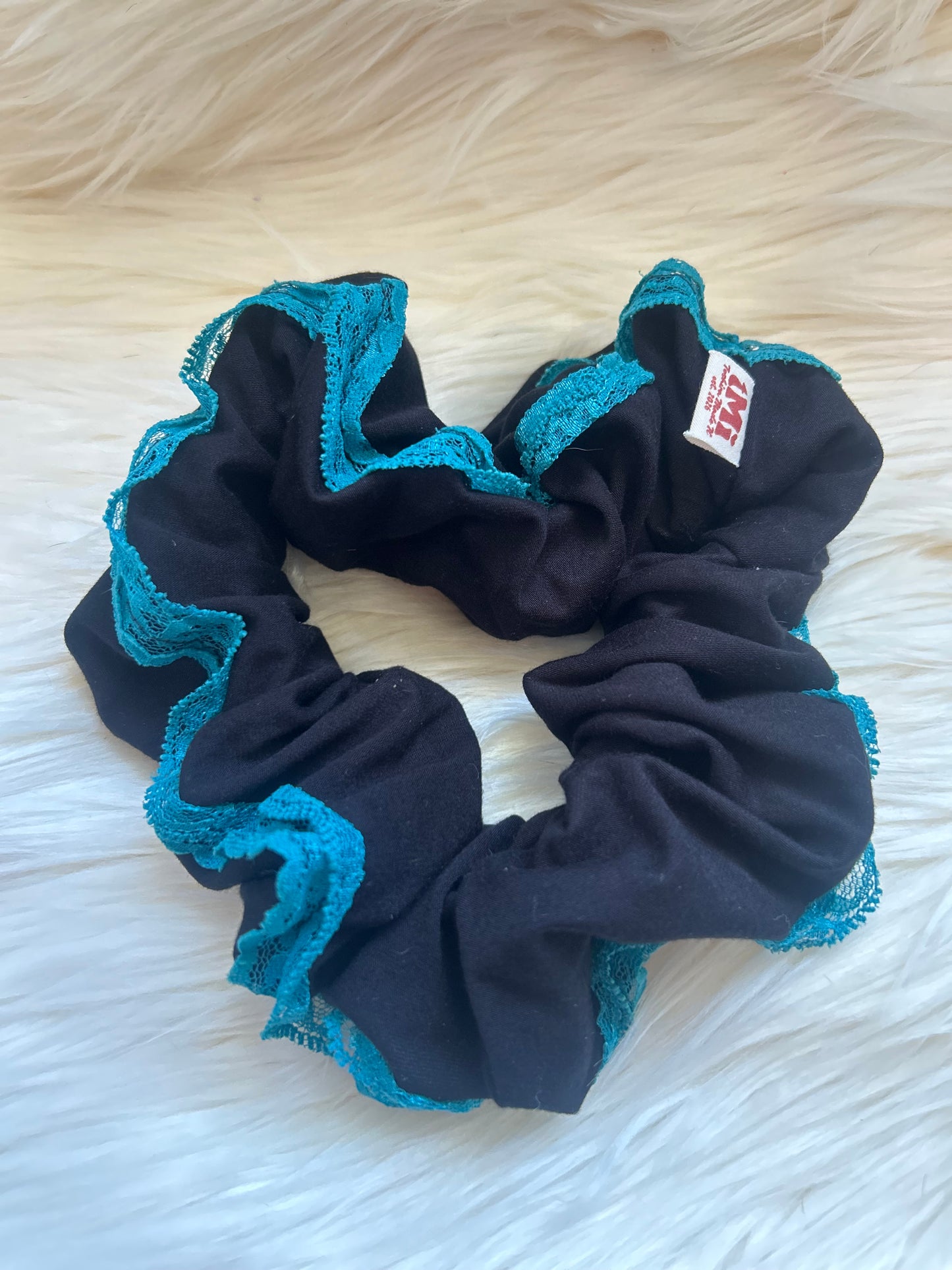 Black scrunchie with blue lace on a white fluffy surface