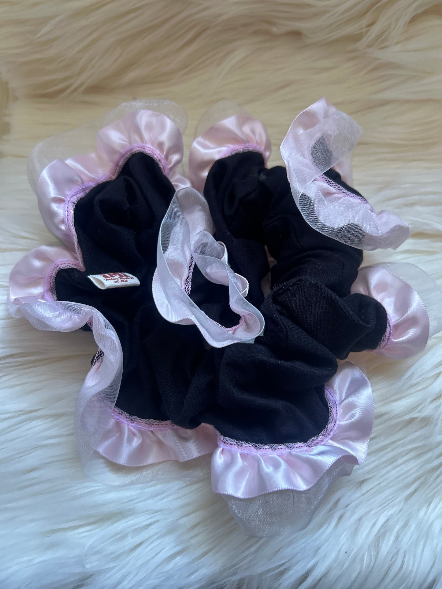 Black scrunchies with pink lace on a white fluffy surface