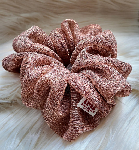 Pink scrunchie with a brand label on a fluffy white background