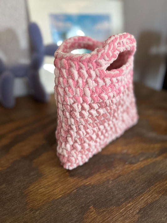 Pink textured bag on a wooden surface with a blurred background